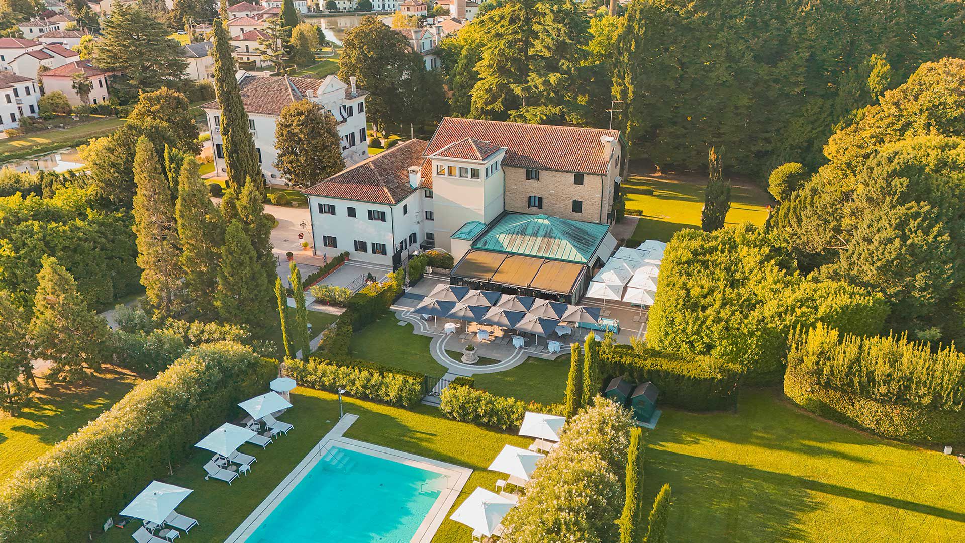 Formal villa front with a garden and mature trees along the canal